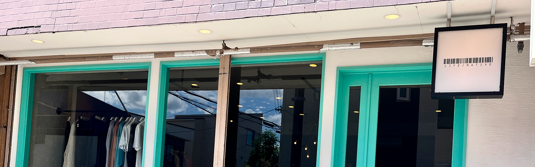 ミントグリーンのドアと窓枠が特徴的な店舗の外観。窓の内側には白いベンチが見える。