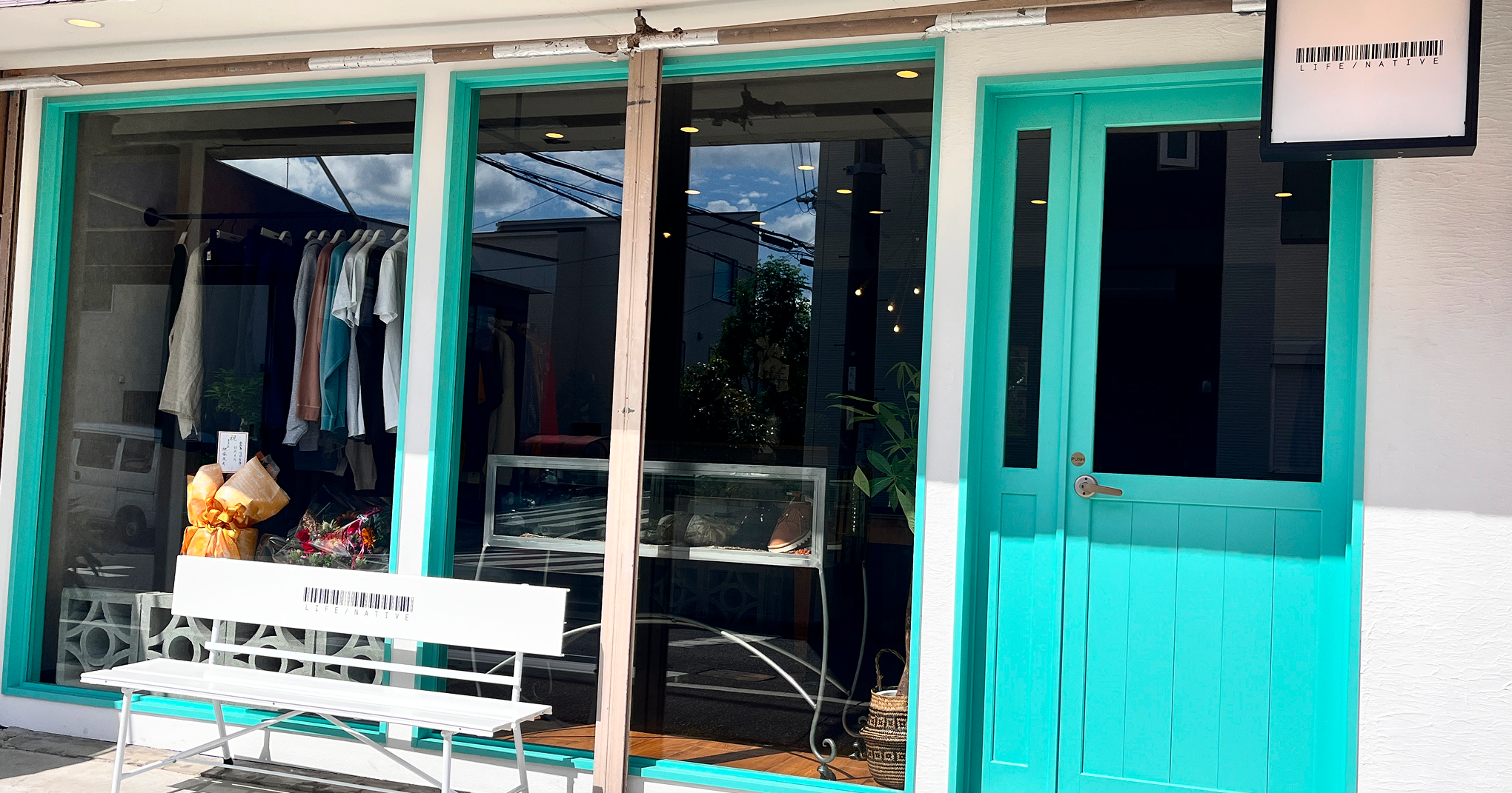 エメラルドグリーンのドアと大きな窓が印象的なセレクトショップの外観。